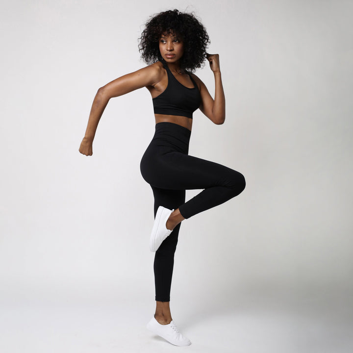 Sleex Activewear Dame traegt schwarze Legging und schwarze Sport BH